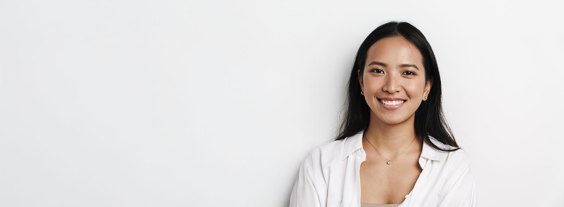 The image shows a woman with a friendly expression standing against a plain background.