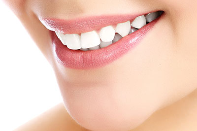 The image displays a close-up view of a person s face, focusing on their teeth and lips, with a blurred background that suggests a dental setting.