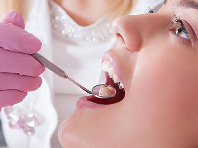 The image shows a person receiving dental treatment with a dentist using tools to work on their teeth.