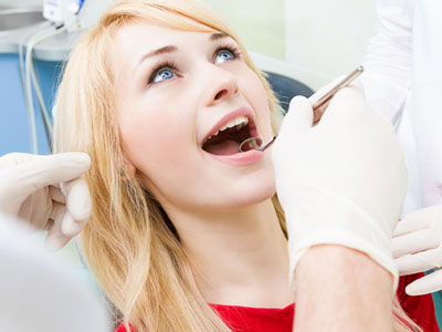 Woman receiving dental care with a smile, surrounded by medical professionals.