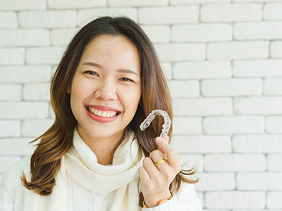 A smiling woman holding up a toothbrush with a smile on her face.